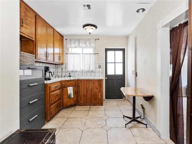 334 N Lomita St, Burbank, CA 91506 - kitchen featuring brown cabinetry, decorative backsplash, tile counters, and light tile patterned floors