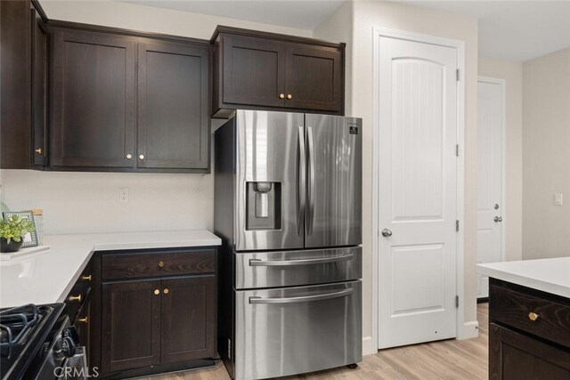 27 Bentwater Loop, Chico, CA 95973 - kitchen featuring stainless steel fridge, dark brown cabinets, light wood-style floors, black gas range oven, and light countertops