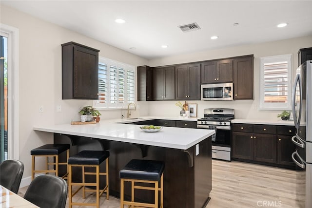 27 Bentwater Loop, Chico, CA 95973 - kitchen featuring stainless steel appliances, a peninsula, light countertops, dark brown cabinetry, and a breakfast bar