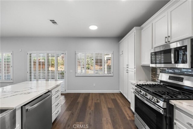 2892 Chuckwagon Rd, Palmdale, CA 93550 - kitchen with appliances with stainless steel finishes, dark wood-type flooring, white cabinets, light stone counters, and backsplash