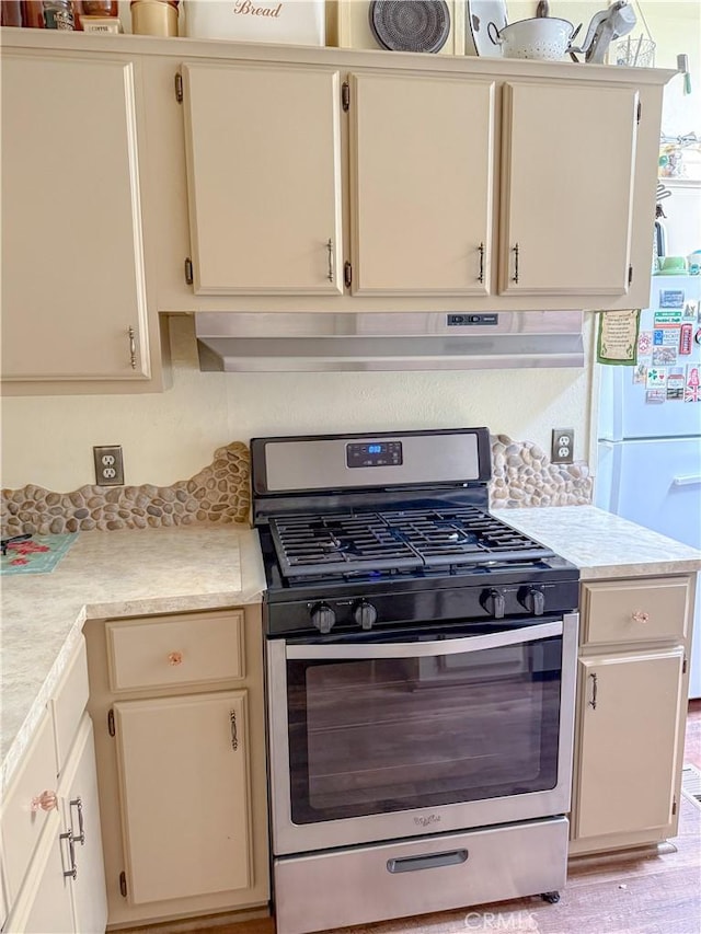 27545 Jasper Way, Castaic, CA 91384 - kitchen with stainless steel gas range oven, light countertops, freestanding refrigerator, under cabinet range hood, and cream cabinetry