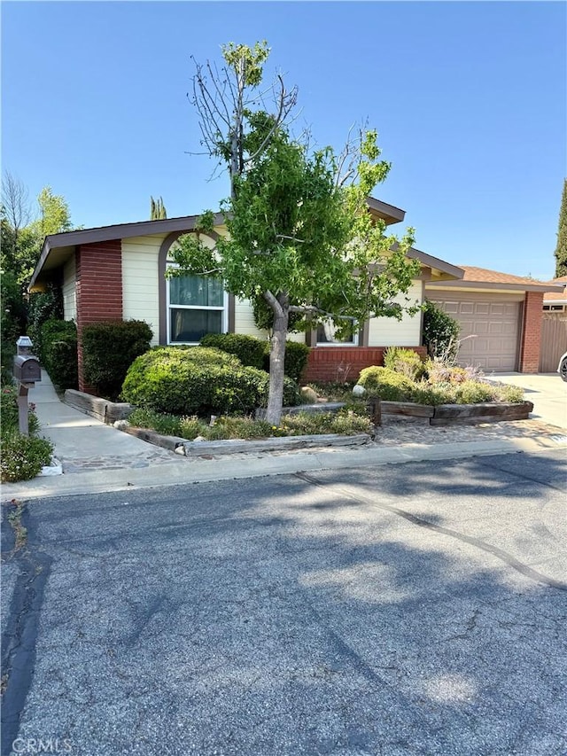 27545 Jasper Way, Castaic, CA 91384 - view of property hidden behind natural elements with an attached garage, concrete driveway, and brick siding