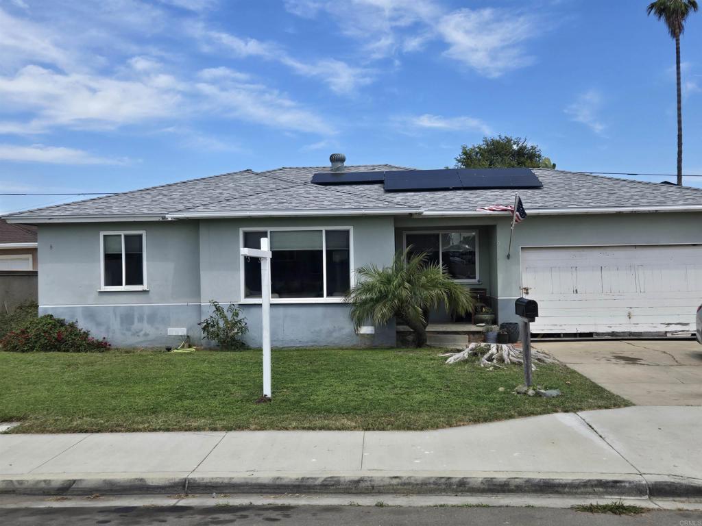 835 Corvina St, Imperial Beach, CA 91932 - ranch-style house with stucco siding, a shingled roof, an attached garage, roof mounted solar panels, and a front lawn