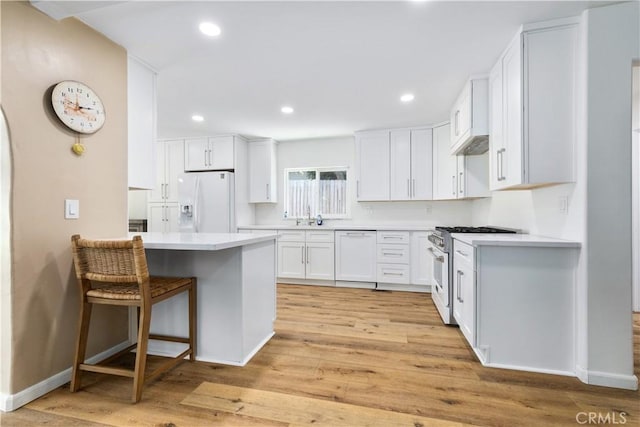 4955 Arizona Ave, Atascadero, CA 93422 - kitchen with white fridge with ice dispenser, high end stainless steel range, paneled dishwasher, light wood-type flooring, and white cabinetry