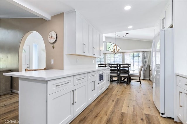 4955 Arizona Ave, Atascadero, CA 93422 - kitchen with freestanding refrigerator, built in microwave, white cabinetry, light wood-style flooring, and lofted ceiling