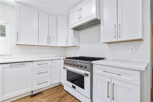 4955 Arizona Ave, Atascadero, CA 93422 - kitchen featuring range with gas stovetop, white cabinets, premium range hood, light wood-type flooring, and light stone counters