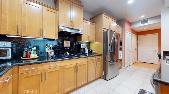 4821 Bakman Ave Unit 405, North Hollywood, CA 91601 - kitchen with stainless steel fridge, under cabinet range hood, dark stone countertops, backsplash, and light tile patterned floors