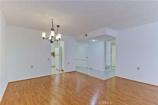 3463 Bahia Blanca W Unit B, Laguna Woods, CA 92637 - unfurnished room featuring light wood-style flooring, a chandelier, and a textured ceiling