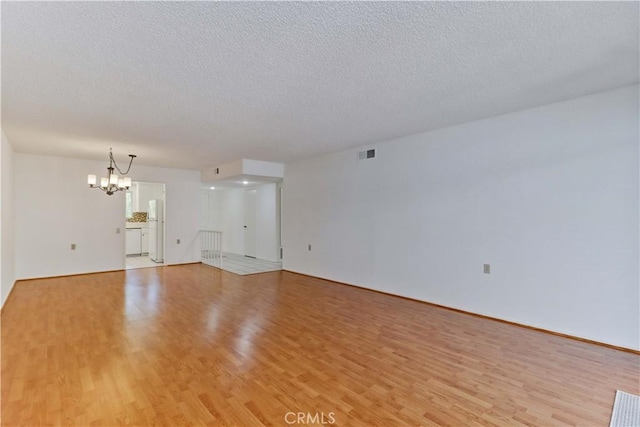 3463 Bahia Blanca W Unit B, Laguna Woods, CA 92637 - unfurnished living room featuring a chandelier, light wood-style floors, and a textured ceiling
