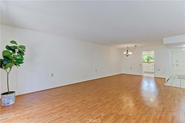 3463 Bahia Blanca W Unit B, Laguna Woods, CA 92637 - unfurnished living room with light wood finished floors, a chandelier, and a textured ceiling