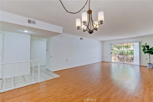 3463 Bahia Blanca W Unit B, Laguna Woods, CA 92637 - unfurnished room with wood finished floors, a chandelier, and a textured ceiling