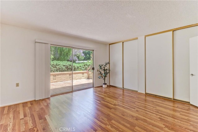 3463 Bahia Blanca W Unit B, Laguna Woods, CA 92637 - unfurnished bedroom featuring multiple closets, access to outside, light wood-style flooring, and a textured ceiling