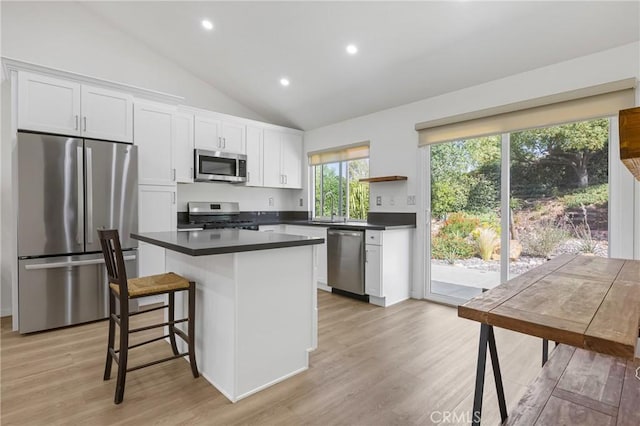 24538 Meadow Grass Way, Moreno Valley, CA 92557 - kitchen with appliances with stainless steel finishes, open shelves, dark countertops, a center island, and vaulted ceiling