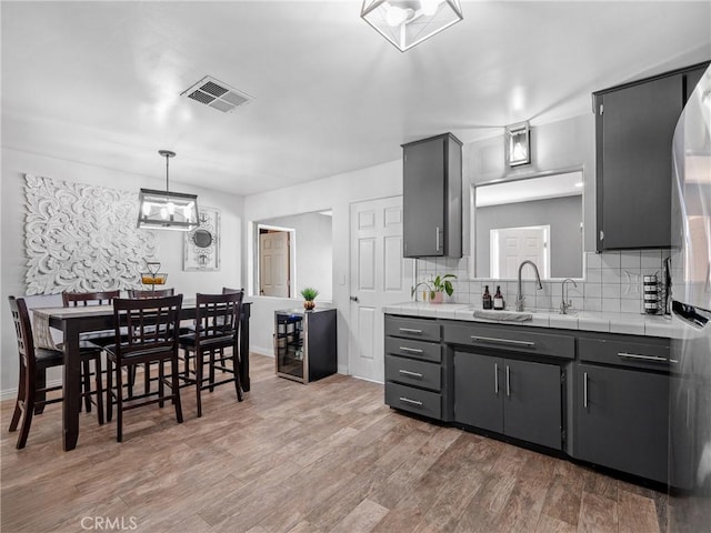 17789 Sycamore St, Hesperia, CA 92345 - kitchen with tile counters, decorative backsplash, wood finished floors, and hanging light fixtures