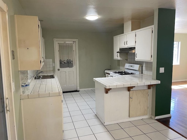 1195 Ilexey Ave, San Diego, CA 92154 - kitchen with gas range gas stove, under cabinet range hood, tile countertops, and backsplash