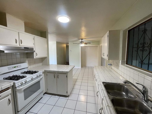 1195 Ilexey Ave, San Diego, CA 92154 - kitchen featuring white gas range oven, under cabinet range hood, tile countertops, light tile patterned floors, and tasteful backsplash
