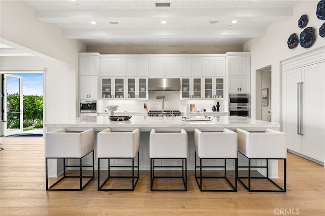 30 Catalina Vista Rd, Ladera Ranch, CA 92694 - kitchen with under cabinet range hood, white cabinetry, a kitchen breakfast bar, and wood ceiling