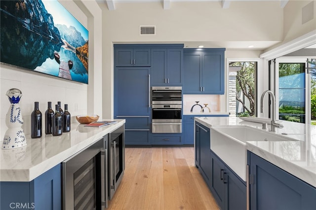 30 Catalina Vista Rd, Ladera Ranch, CA 92694 - kitchen with wine cooler, blue cabinets, light wood finished floors, tasteful backsplash, and beam ceiling