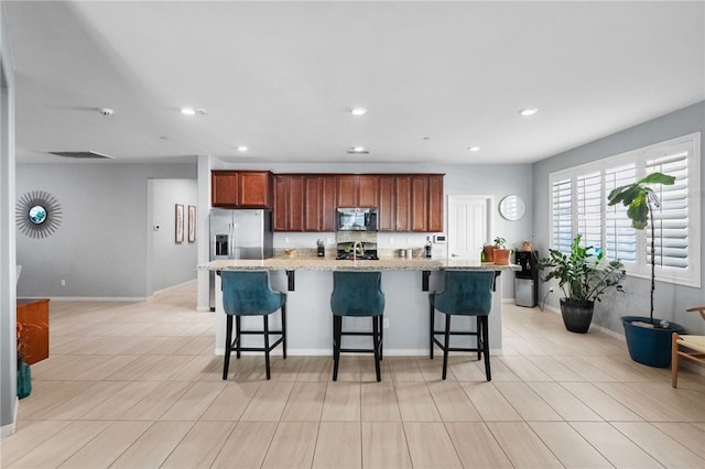 4040 Quartzite Ln, San Bernardino, CA 92407 - kitchen with stainless steel appliances, a large island with sink, a breakfast bar area, light stone countertops, and recessed lighting