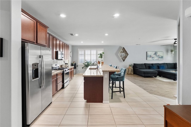 4040 Quartzite Ln, San Bernardino, CA 92407 - kitchen with stainless steel appliances, light tile patterned flooring, a kitchen bar, recessed lighting, and an island with sink
