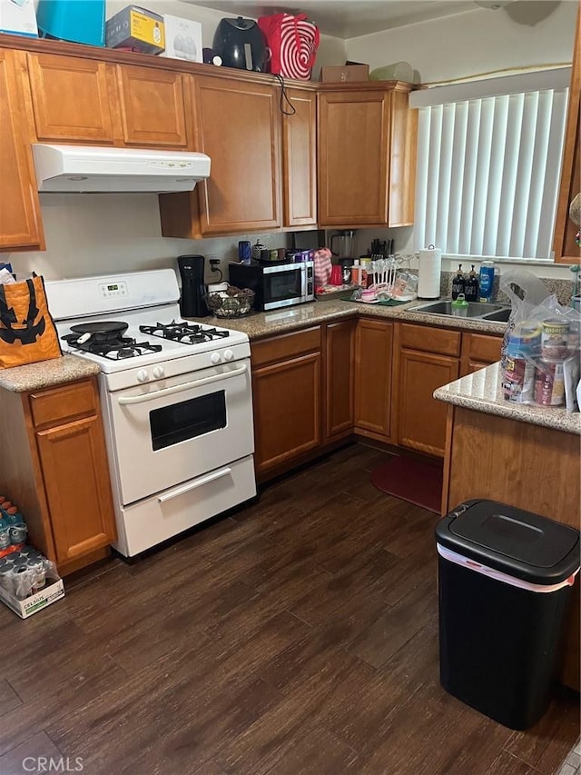 12843 Columbia Way, Downey, CA 90242 - kitchen with gas range gas stove, under cabinet range hood, dark wood-style flooring, stainless steel microwave, and light countertops
