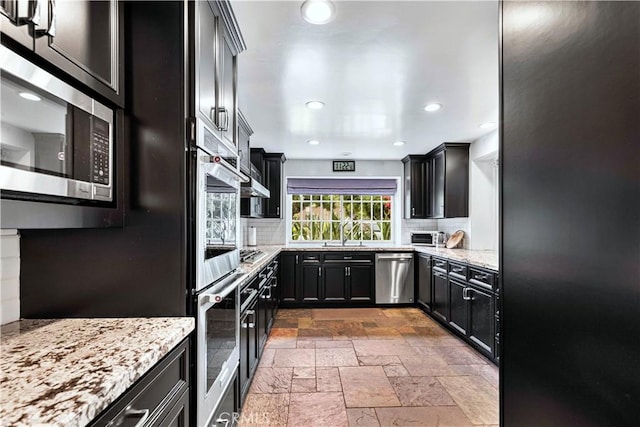 17437 Tarzana St, Encino, CA 91316 - kitchen featuring stainless steel appliances, stone tile floors, backsplash, light stone counters, and recessed lighting