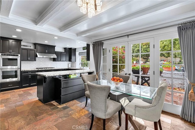 17437 Tarzana St, Encino, CA 91316 - kitchen with stainless steel double oven, dark cabinets, stone tile floors, beamed ceiling, and decorative backsplash