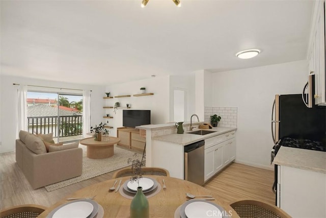 4727 W 147th St Unit 133, Lawndale, CA 90260 - kitchen featuring appliances with stainless steel finishes, open floor plan, a peninsula, and light wood-type flooring