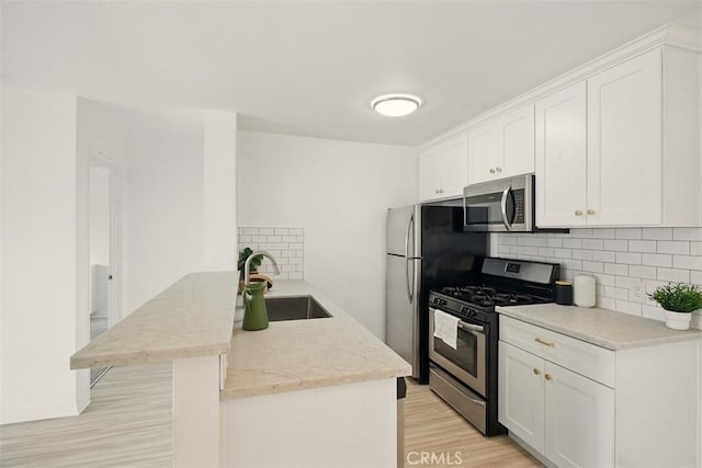 4727 W 147th St Unit 133, Lawndale, CA 90260 - kitchen with appliances with stainless steel finishes, backsplash, light wood-style flooring, white cabinetry, and a peninsula