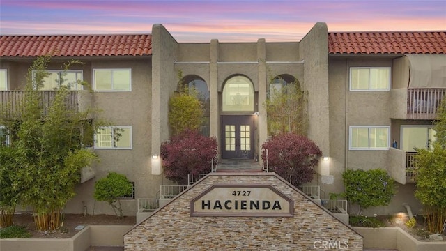 4727 W 147th St Unit 133, Lawndale, CA 90260 - exterior entry at dusk with french doors, stucco siding, and a tiled roof