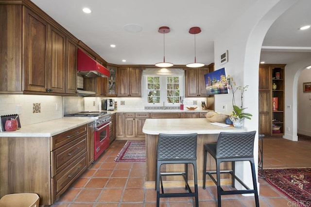308 Sunset Dr Unit A, Encinitas, CA 92024 - kitchen featuring stainless steel range, arched walkways, extractor fan, light countertops, and decorative backsplash