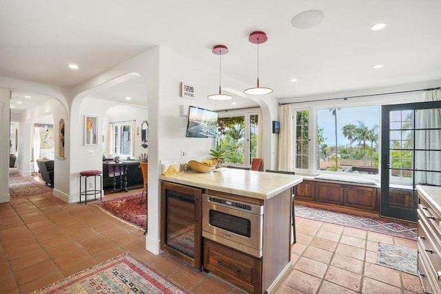 308 Sunset Dr Unit A, Encinitas, CA 92024 - kitchen with beverage cooler, light countertops, arched walkways, recessed lighting, and hanging light fixtures
