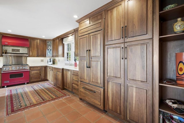 308 Sunset Dr Unit A, Encinitas, CA 92024 - kitchen with luxury stove, premium range hood, light tile patterned floors, light countertops, and brown cabinetry