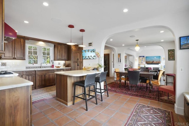 308 Sunset Dr Unit A, Encinitas, CA 92024 - kitchen with arched walkways, a kitchen bar, light countertops, recessed lighting, and backsplash