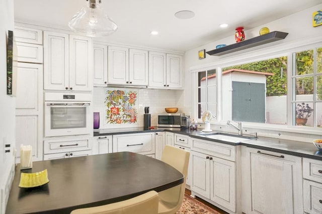 308 Sunset Dr Unit A, Encinitas, CA 92024 - kitchen featuring white oven, dark countertops, stainless steel microwave, decorative backsplash, and recessed lighting