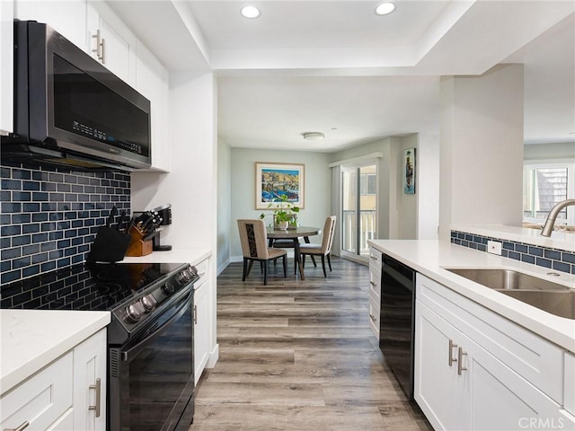 625 Esplanade Unit 29, Redondo Beach, CA 90277 - kitchen featuring black appliances, recessed lighting, light wood finished floors, tasteful backsplash, and white cabinetry
