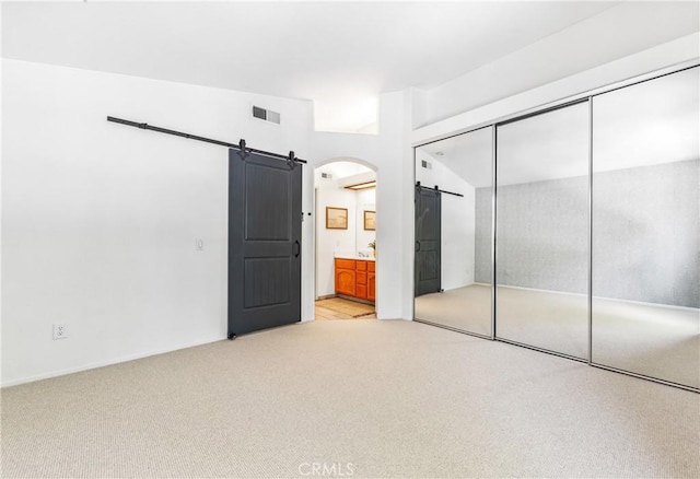 17 Indigo Pl, Aliso Viejo, CA 92656 - unfurnished bedroom with a barn door, light carpet, a closet, ensuite bath, and arched walkways