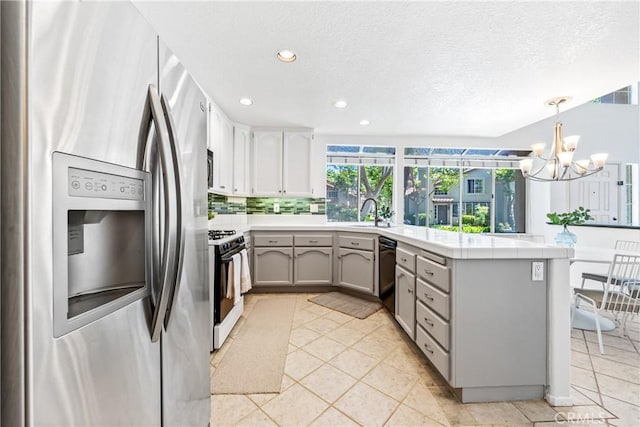 17 Indigo Pl, Aliso Viejo, CA 92656 - kitchen featuring stainless steel fridge, gas range oven, a peninsula, light countertops, and a chandelier