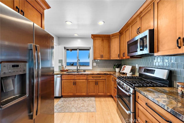 32055 Virginia Way, Laguna Beach, CA 92651 - kitchen with stainless steel appliances, brown cabinetry, light wood-style floors, dark stone countertops, and recessed lighting