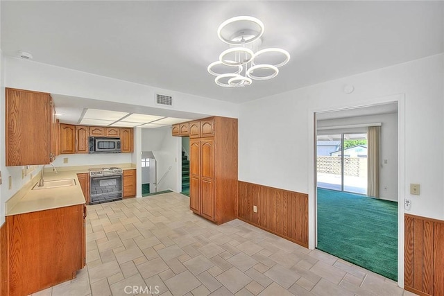 9465 Palo Verde Ave, Fontana, CA 92335 - kitchen featuring stove, stainless steel microwave, brown cabinets, wainscoting, and wooden walls