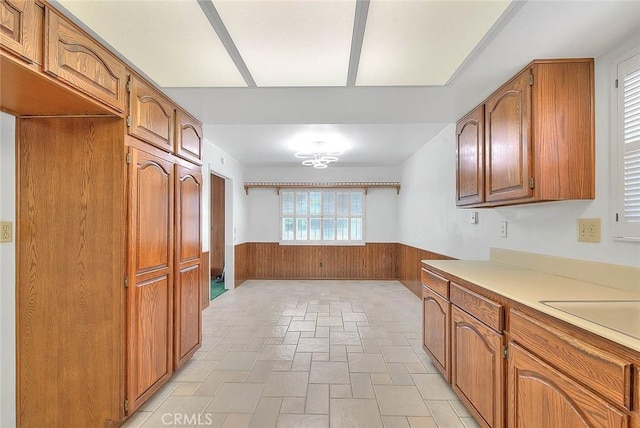 9465 Palo Verde Ave, Fontana, CA 92335 - kitchen with wainscoting, brown cabinets, wooden walls, and light countertops