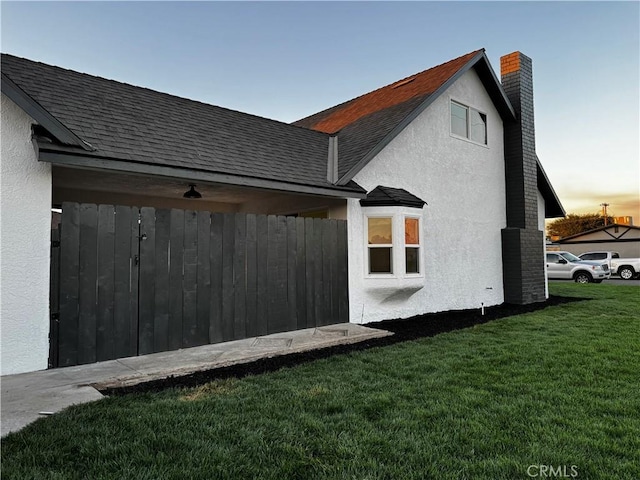 3009 Delburn St, Bakersfield, CA 93304 - rear view of house with a chimney, stucco siding, a lawn, and roof with shingles