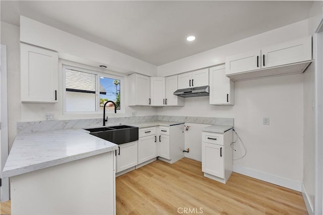 3009 Delburn St, Bakersfield, CA 93304 - kitchen with under cabinet range hood, light stone countertops, light wood-type flooring, white cabinets, and a peninsula
