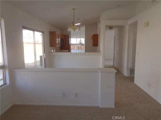 3407 Amber St, Rosamond, CA 93560 - kitchen featuring light carpet, a chandelier, black microwave, brown cabinets, and decorative light fixtures