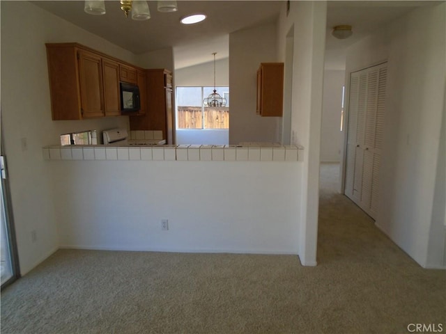 3407 Amber St, Rosamond, CA 93560 - kitchen featuring a chandelier, light colored carpet, black microwave, brown cabinetry, and lofted ceiling