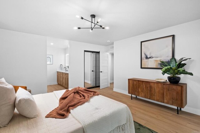 10594 Rookwood Dr, San Diego, CA 92131 - bedroom with light wood-type flooring, a chandelier, and connected bathroom