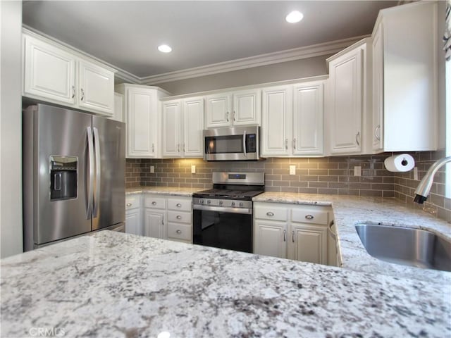 11961 Limestone Ct, Yucaipa, CA 92399 - kitchen featuring stainless steel appliances, crown molding, white cabinetry, decorative backsplash, and light stone countertops