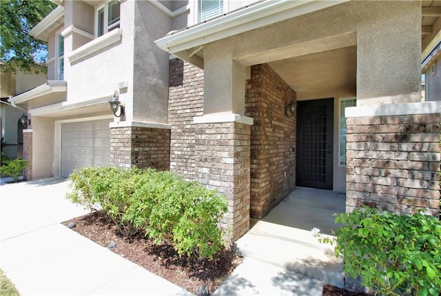 11961 Limestone Ct, Yucaipa, CA 92399 - doorway to property featuring stucco siding, an attached garage, and brick siding
