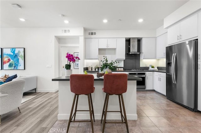 2526 Nolita, Irvine, CA 92612 - kitchen featuring appliances with stainless steel finishes, wall chimney exhaust hood, dark countertops, a kitchen bar, and recessed lighting