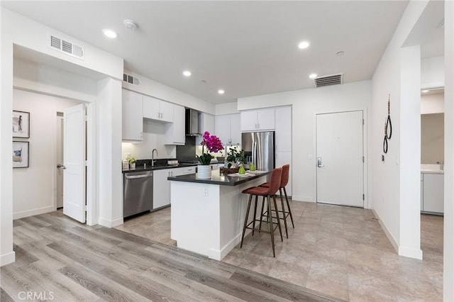 2526 Nolita, Irvine, CA 92612 - kitchen featuring stainless steel appliances, a breakfast bar area, white cabinetry, dark countertops, and a kitchen island